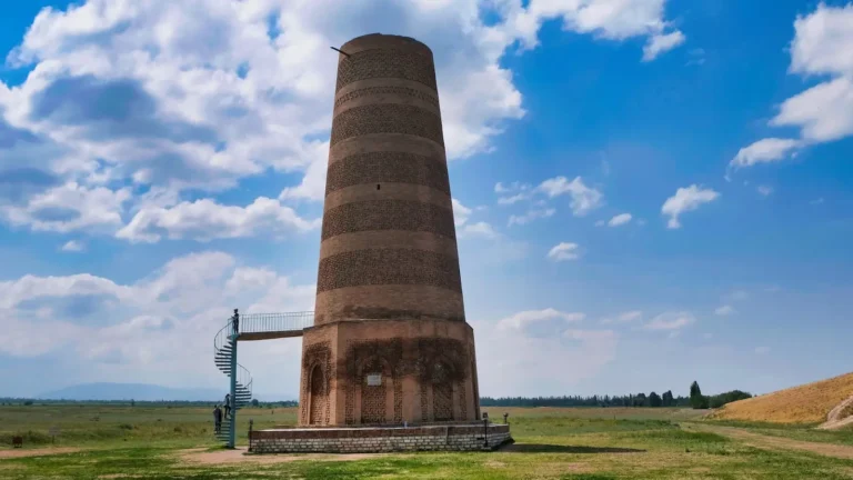 Ancient Burana Tower in Kyrgyzstan, a historical minaret against a blue sky with clouds