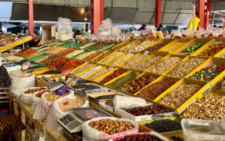 Vibrant Osh Bazaar in Bishkek, displaying arrays of dried fruits, nuts, and spices in colorful bins.